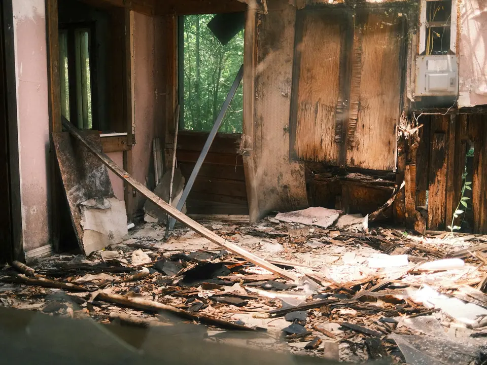 A room gutted by fire, with charred framing and debris on the floor